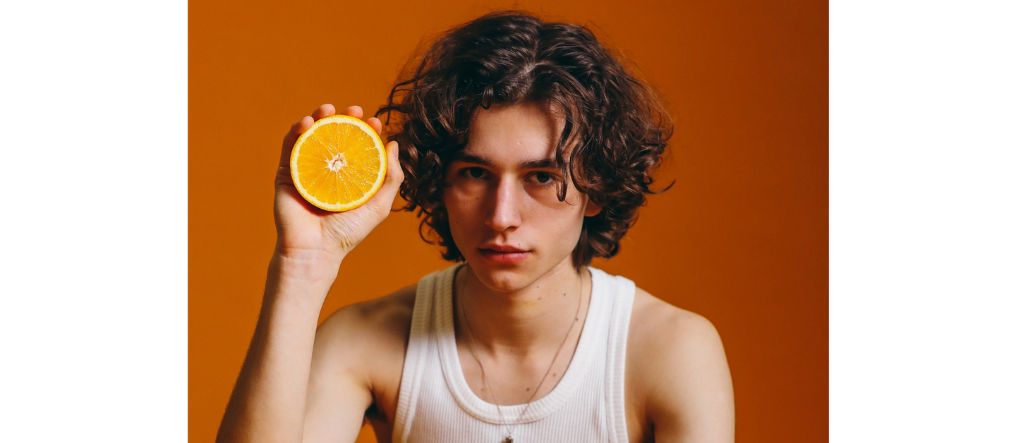 Curly-haired individual with citrus, representing vitamin-rich hair care.